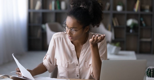 Woman looking at piece of paper confused